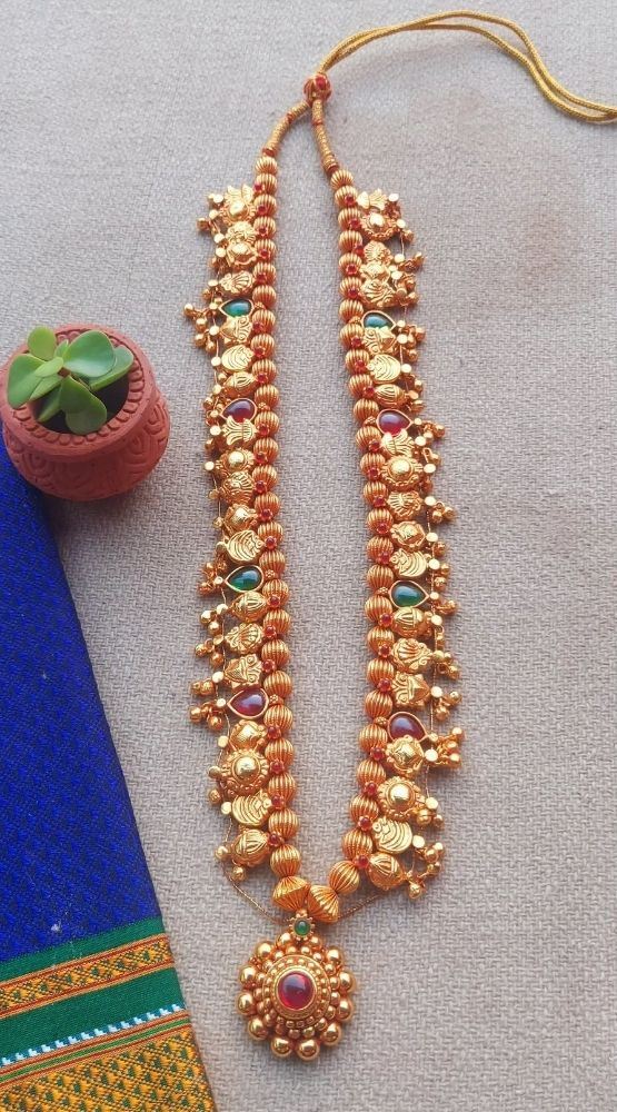 Geru Plated Kolhapuri Saaj with Pendant from Mugdha Jewellery Store: Traditional Indian jewelry featuring intricate gold-toned beads and a vibrant pendant.