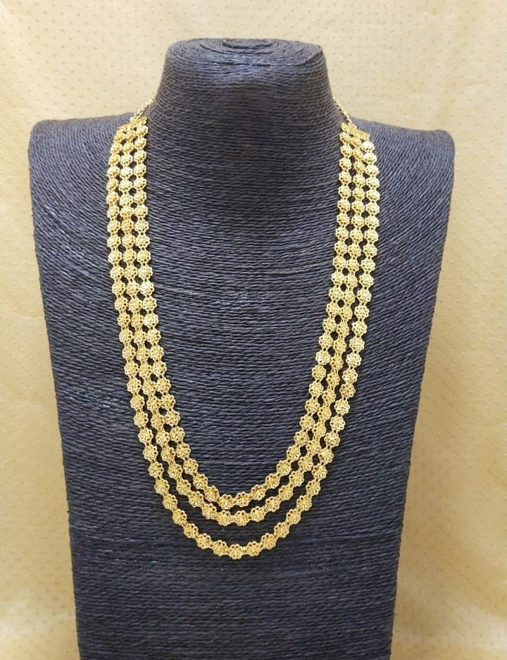 Elegant multi-strand gold tone beaded necklace displayed on a black display stand in the image.