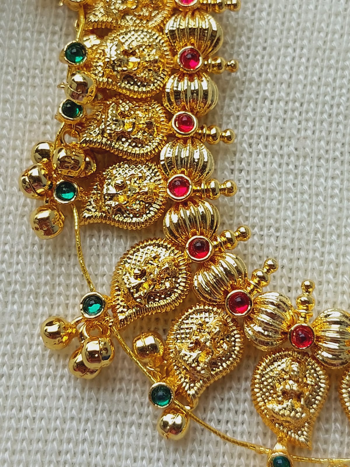 Ornate golden necklace with elaborate beaded and floral details, adorned with colorful gemstones in an intricate ethnic design from the Mugdha Jewellery Store.