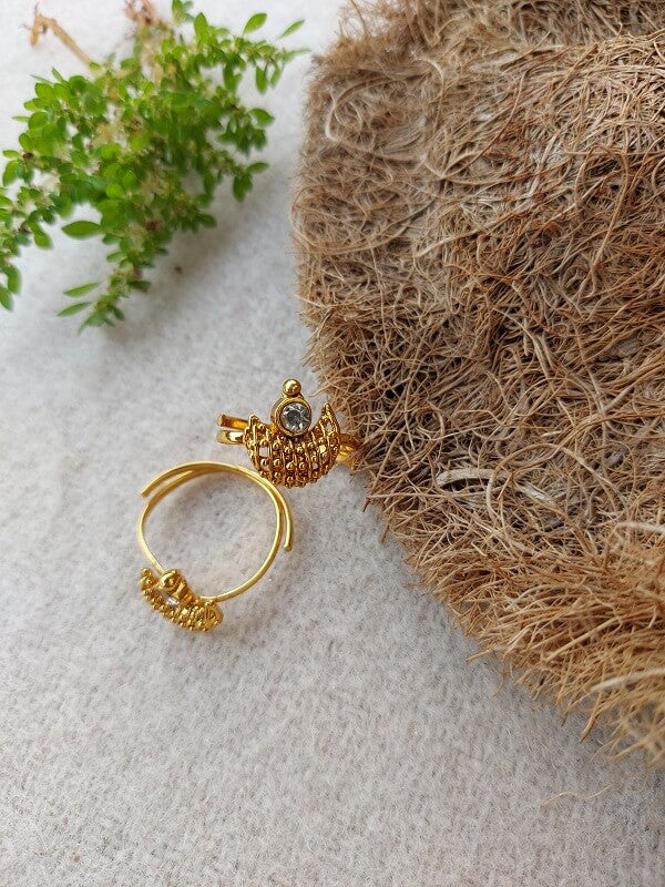 Golden ornate toe ring with intricate flower design on a natural, woven backdrop