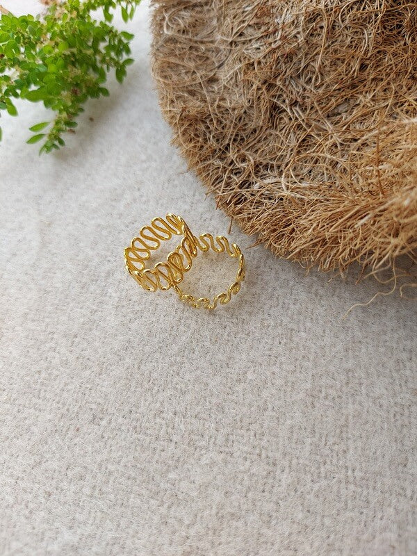 Elegant gold toe ring against a natural, textured background with greenery accents from the Mugdha Jewellery Store.
