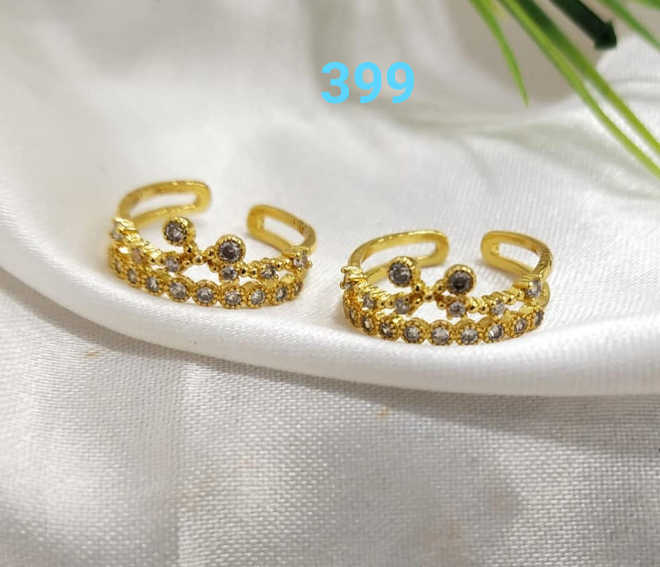 Elegant gold-tone designer toe rings with sparkling white gemstones, displayed on a white fabric background.