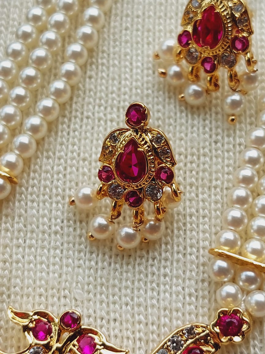 Designer Two Peacock Short Haar from Mugdha Jewellery Store. Striking gold-toned necklace with ornate ruby-colored gemstones and lustrous pearl accents.