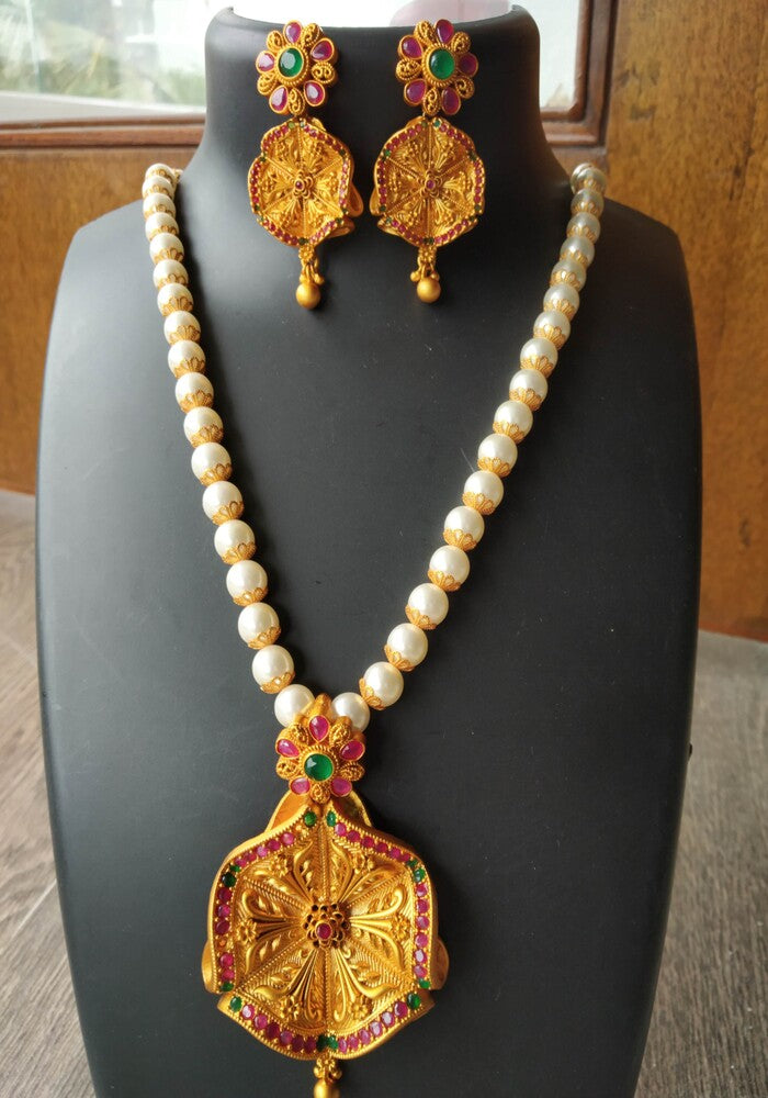 Elegant Pearl Flower Jewelry Set: Ornate gold pendant with vibrant gemstones, paired with a pearl necklace and matching floral earrings, displayed on a black background.