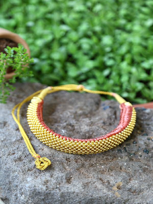 Elegant golden beaded bracelet on stone with natural greenery background