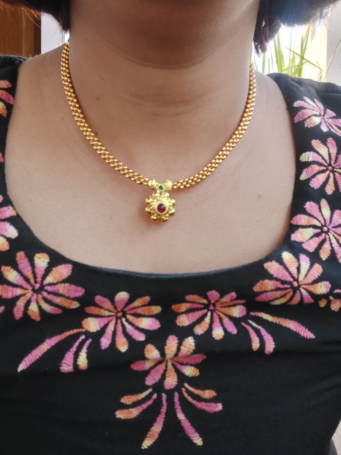 Traditional Thushi Necklace from Mugdha Jewellery Store: Golden beaded chain with floral pendant featuring a vibrant red gemstone accent.