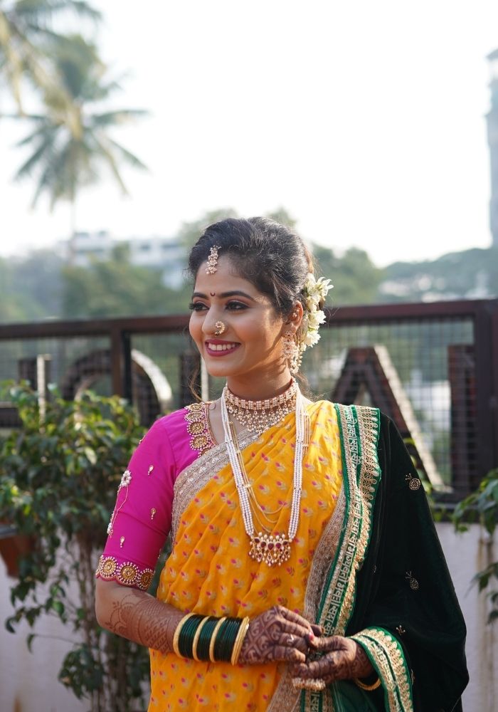 Vibrant traditional Indian jewelry, including a necklace with three strands of red gemstones, worn by a smiling woman in a colorful sari.