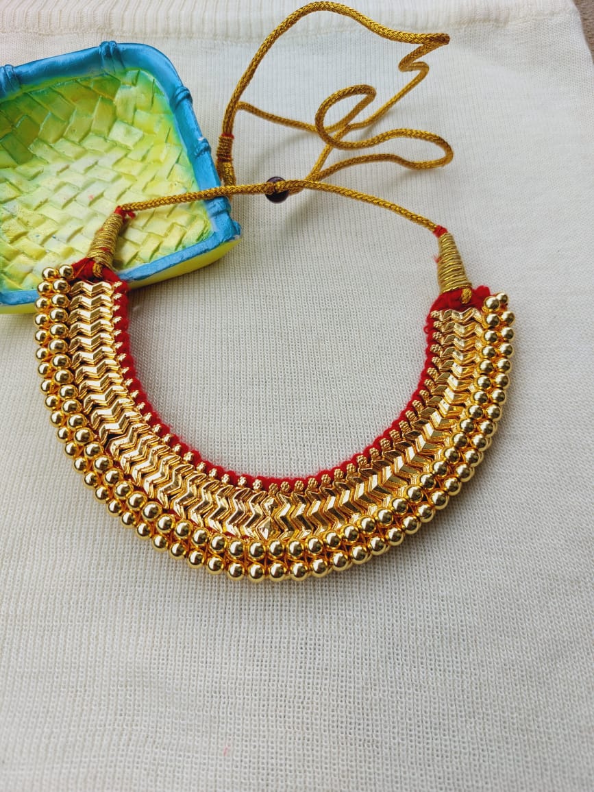 Ornate Kolhapuri Vajratik Necklace - Handcrafted gold-toned metal necklace with intricate bead patterns, displayed on a textured light background.