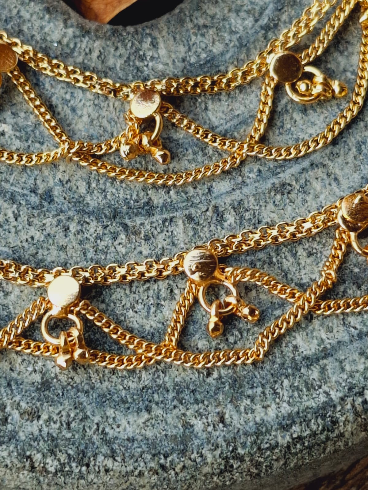 Designer Golden Ear Chain - Elegant golden chains with delicate charms, showcased on a serene stone surface.