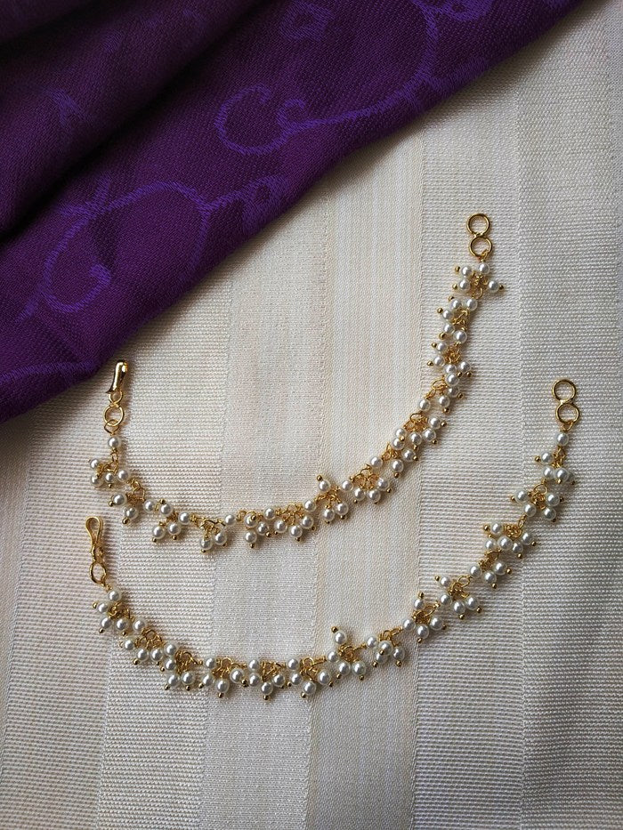 Elegant gold and pearl necklace with delicate floral design on a purple fabric background in the Mugdha Jewellery Store.