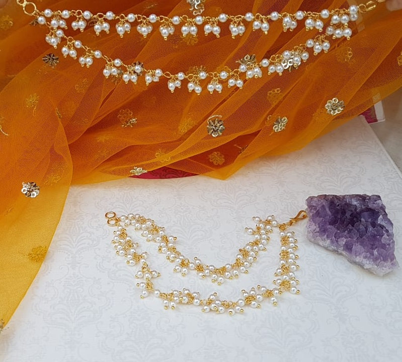 Double-layered pearl well with floral accents on vibrant orange fabric, surrounded by sparkling gemstones and a natural amethyst crystal.