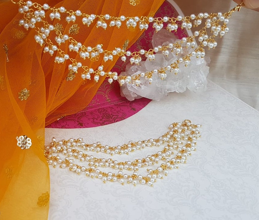 Elegant triple-layered pearl necklace with sparkling accents, showcased amidst vibrant orange and pink fabrics