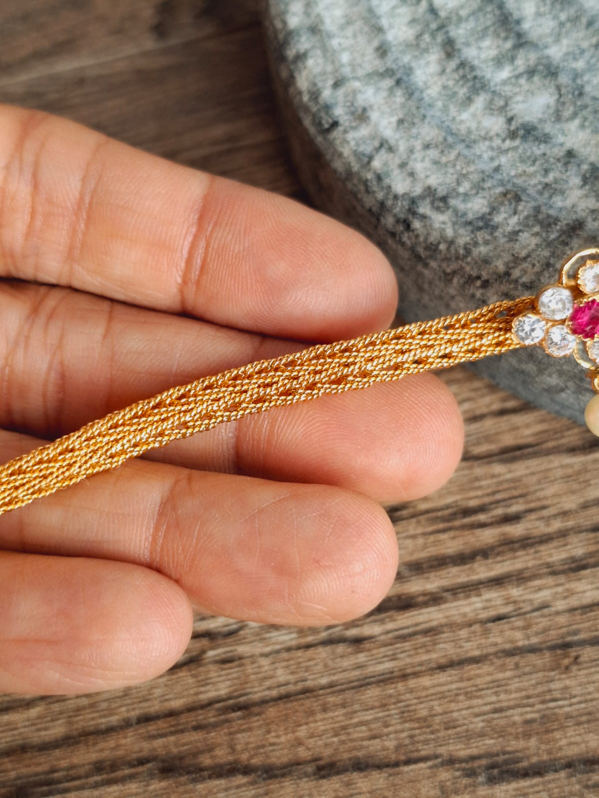 Elegant gold floral choker with vibrant gemstones, showcased on a wooden surface