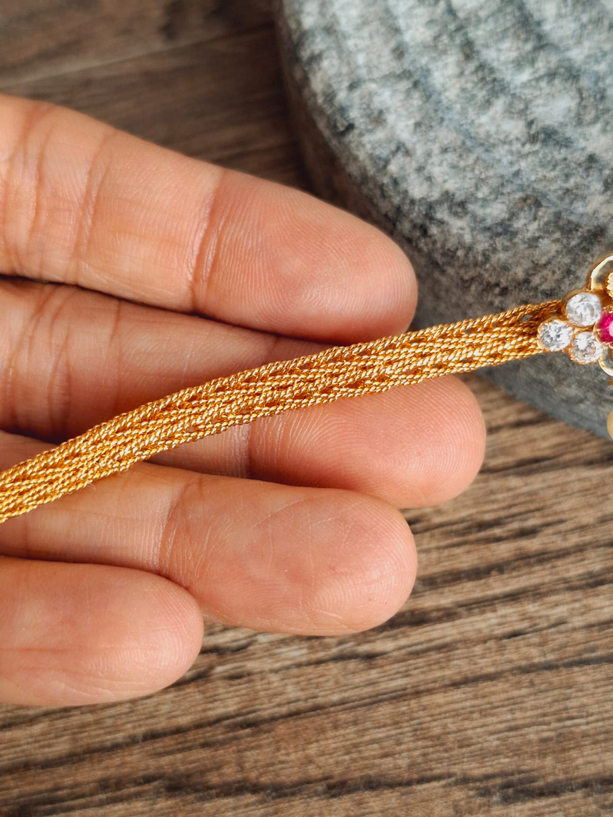 Gold plated floral-inspired oval choker and armband on wooden surface