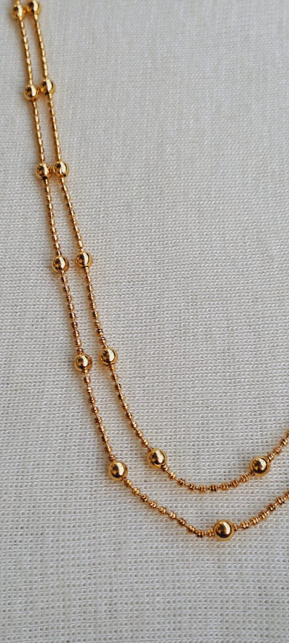 Elegant gold chained necklace from Mugdha Jewellery Store featuring a layered double-strand design with delicate beads and sleek links.