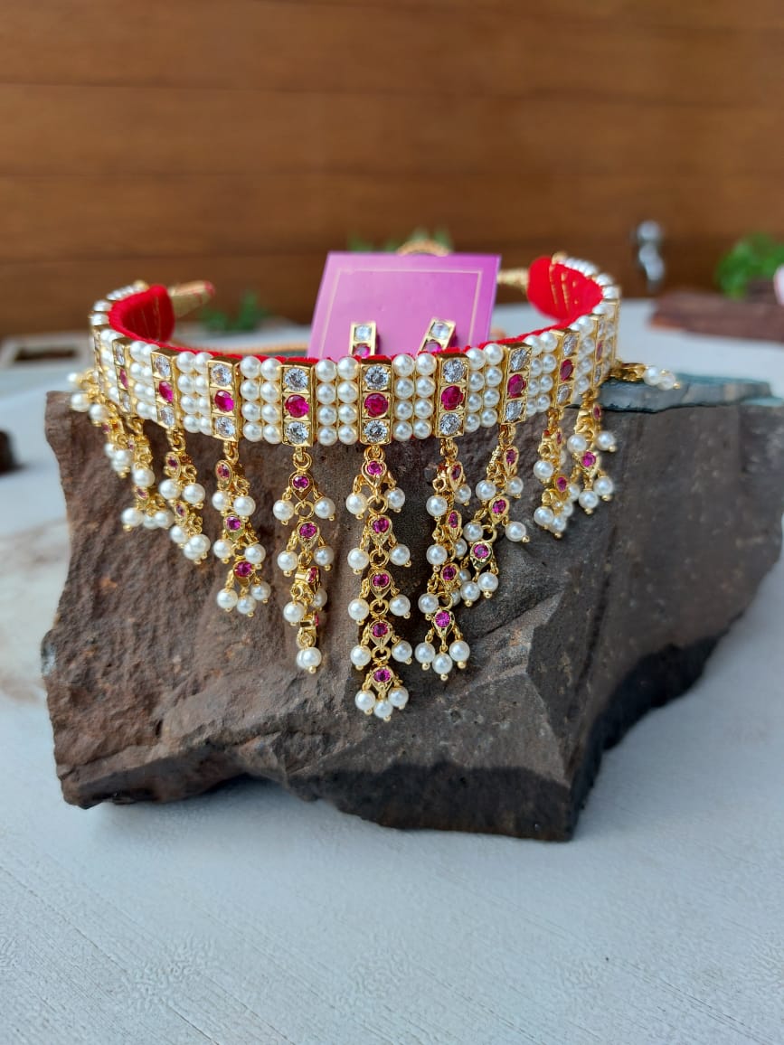 Dark pink and white traditional Indian necklace with pearl and crystal embellishments on a stone surface