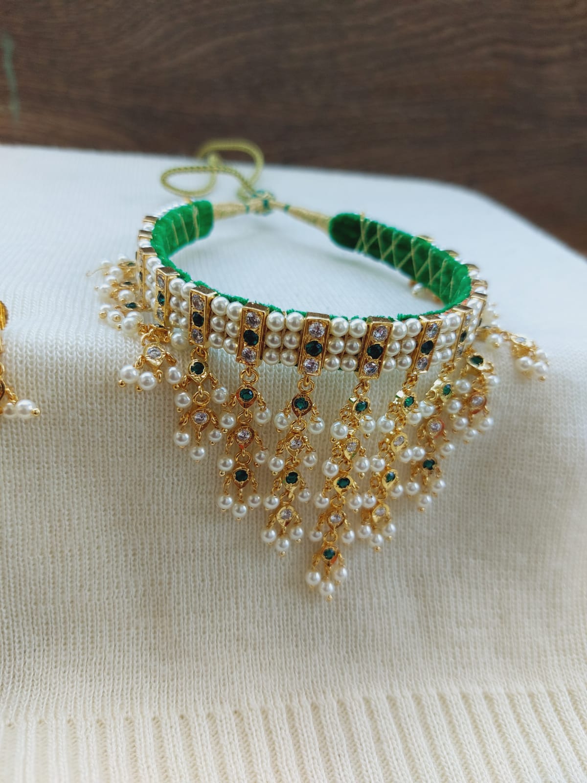 Elegant pearl and crystal choker necklace with green accents, displayed on a white sweater.