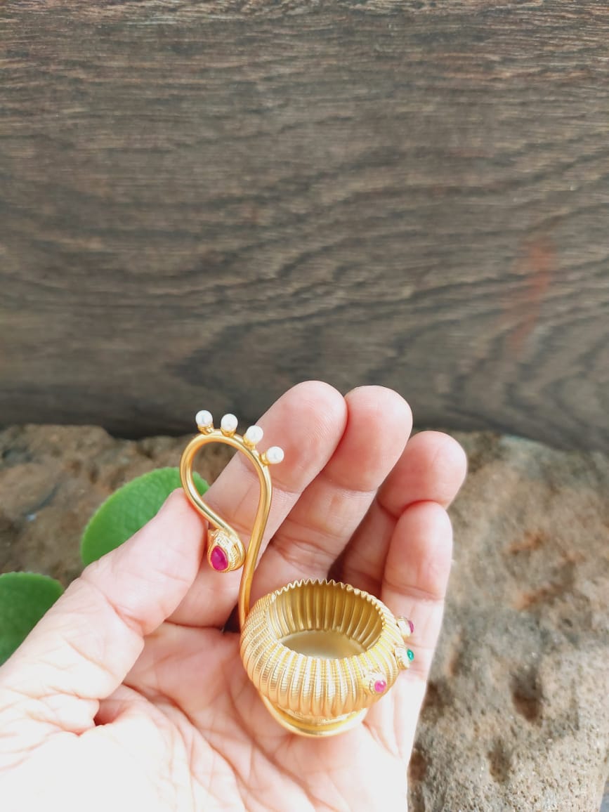 Haldi Kumkum Karanda 3 - Vibrant golden jewelry piece with delicate floral motifs held in hand against rustic wooden background from Mugdha Jewellery Store.