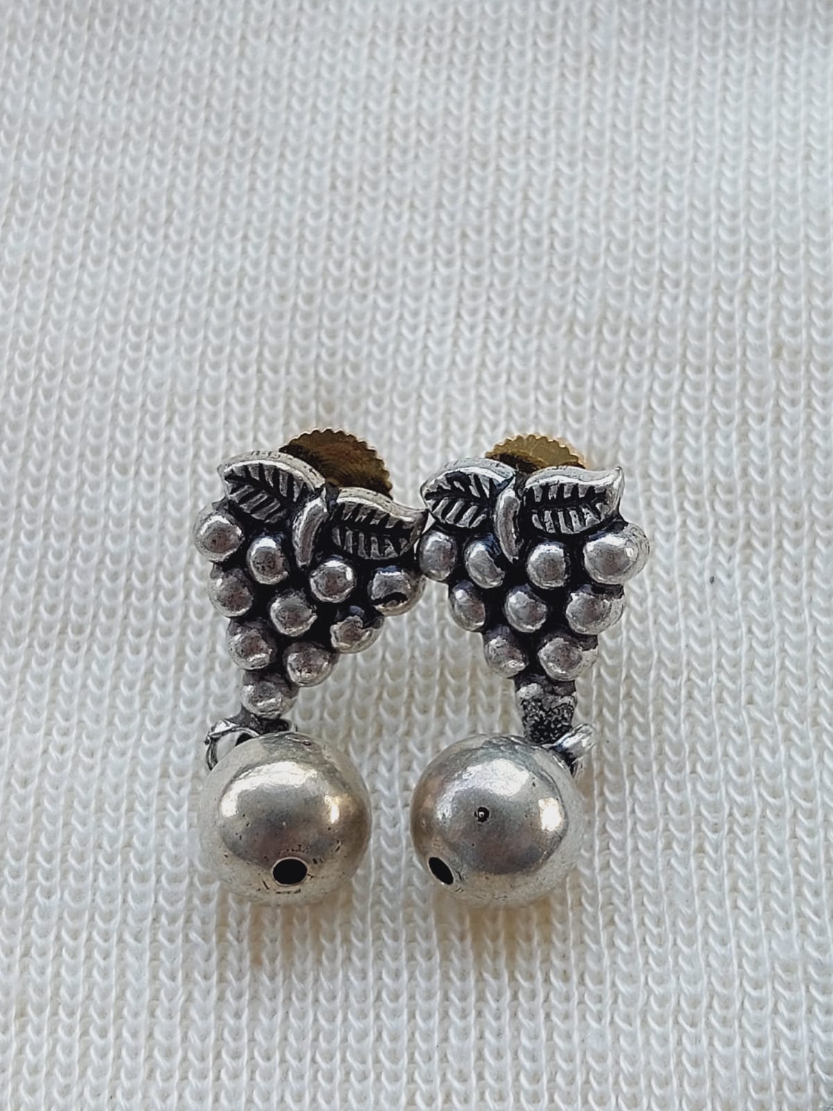 Oxidized metal mangalsutra pendant featuring intricate grape cluster design with dangling pearl accents, displayed on plain white knitted background.