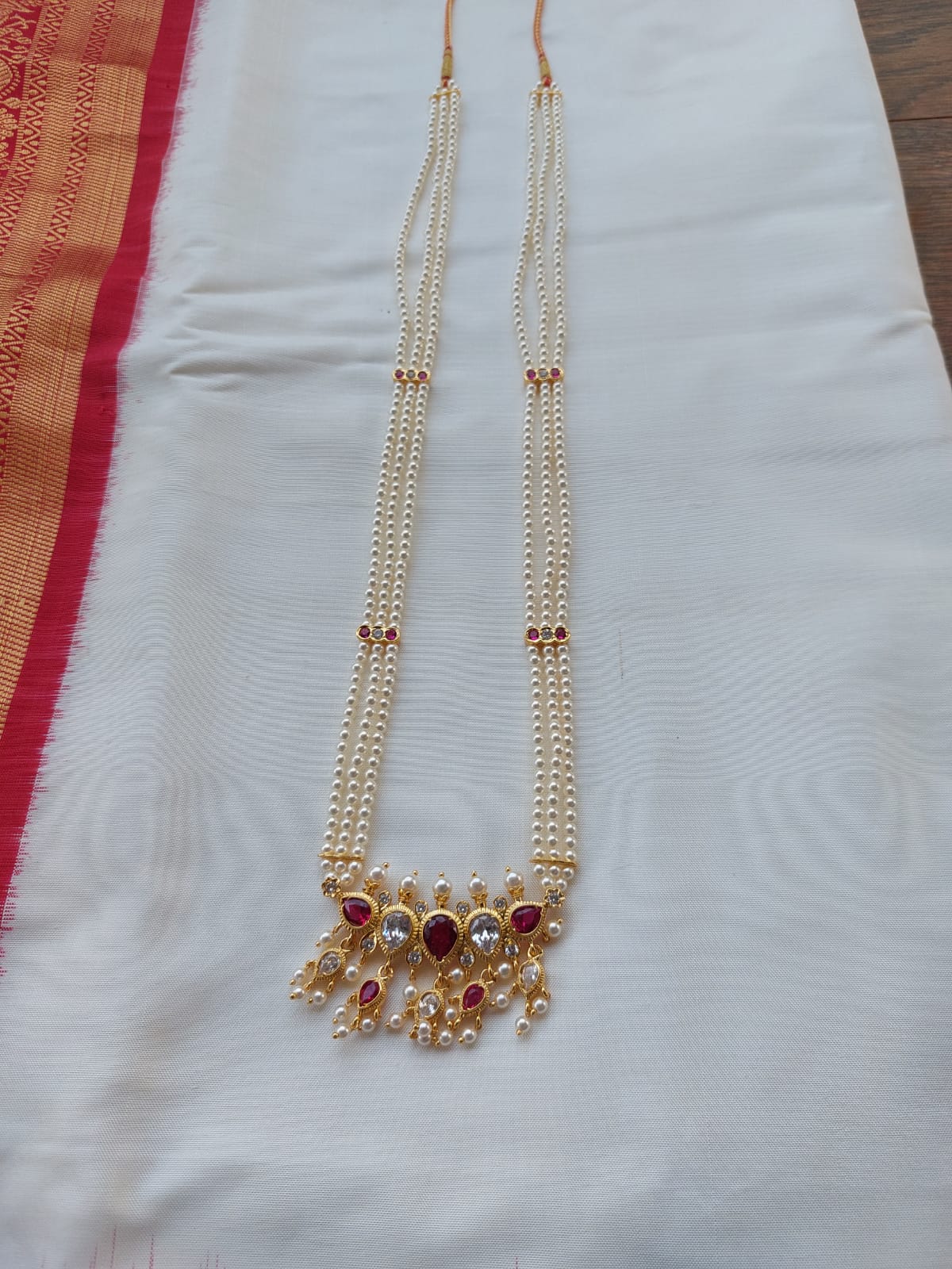 Elegant gold-toned multi-chain long necklace with vibrant red and yellow gemstones, showcased on a plain white background.