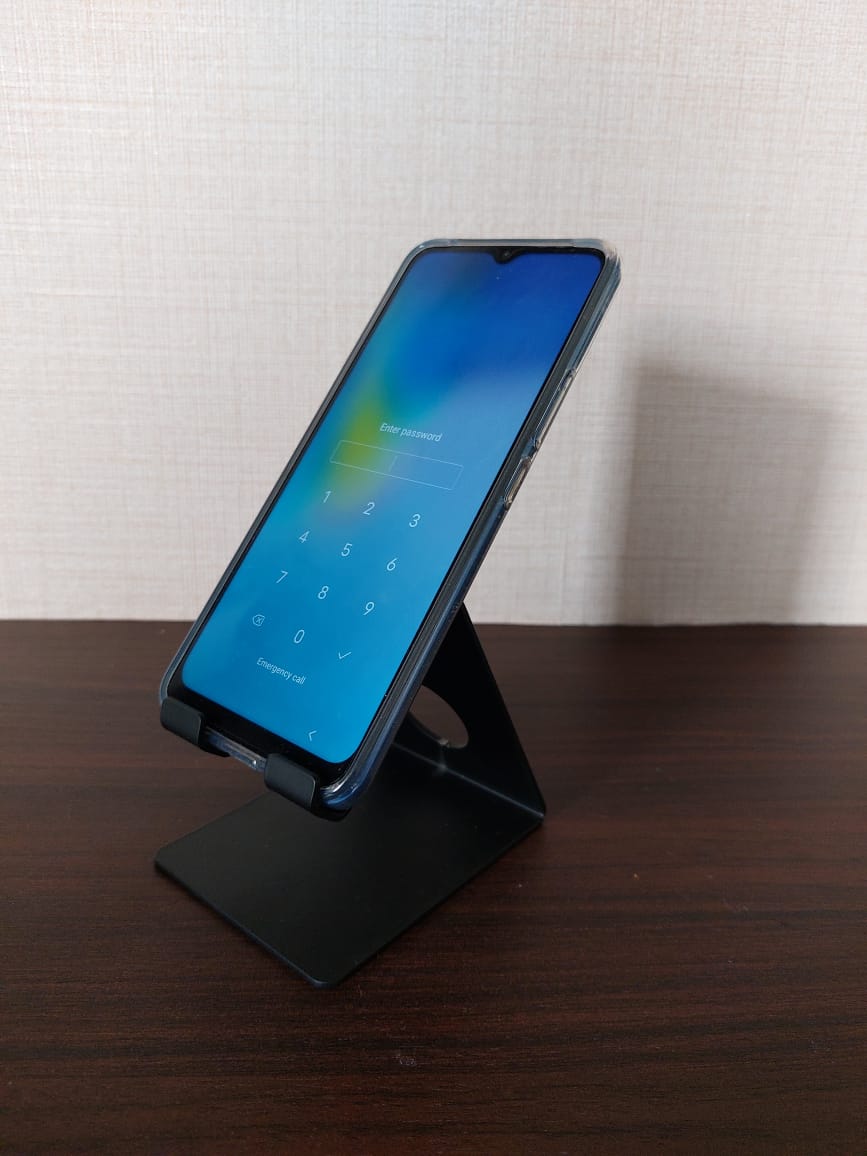 Sturdy mobile holder for Mugdha Jewellery Store, designed to securely support smartphones on a dark wooden surface.