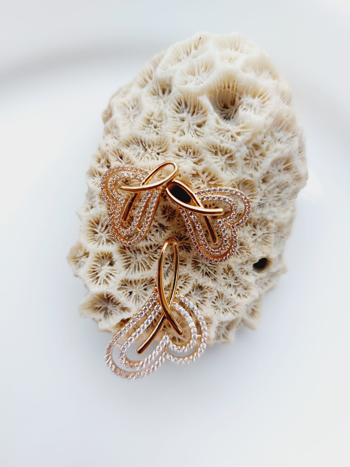 Rose Gold Plated American Diamond High Quality Heart Pendant Set displayed on a natural coral rock against a white background.