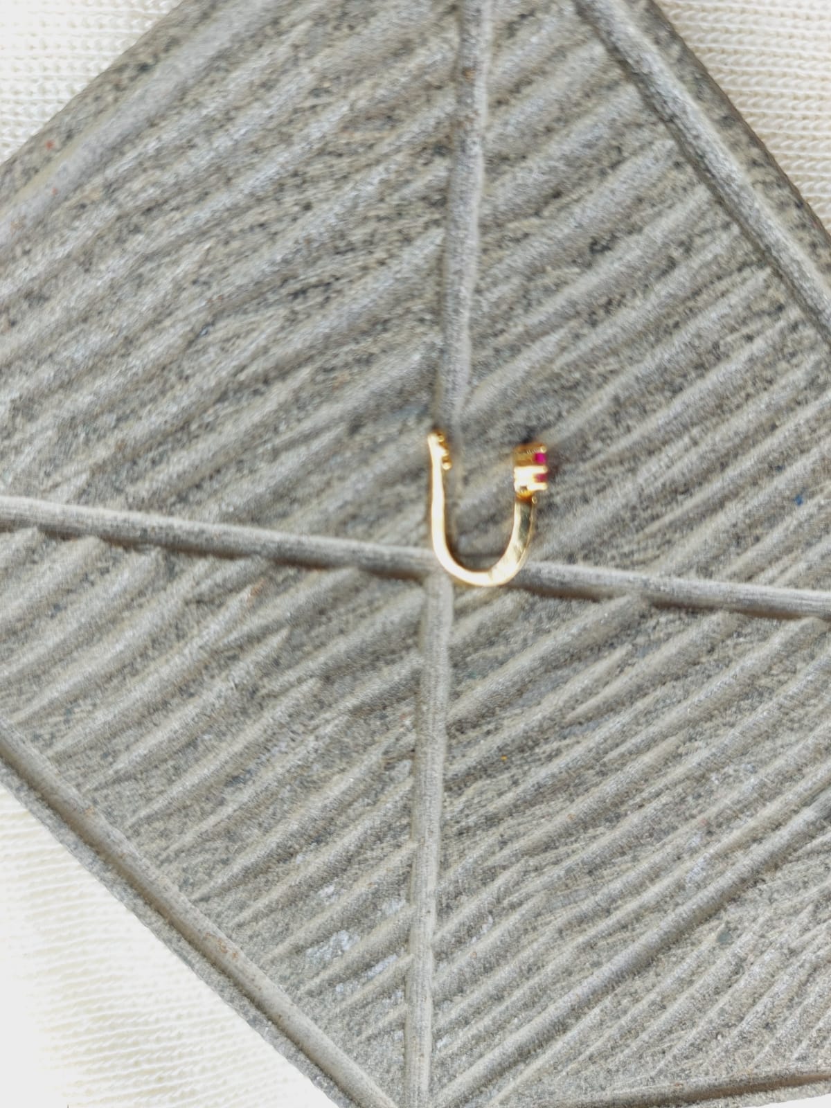 Cute red stone nose pin on a grey textile background