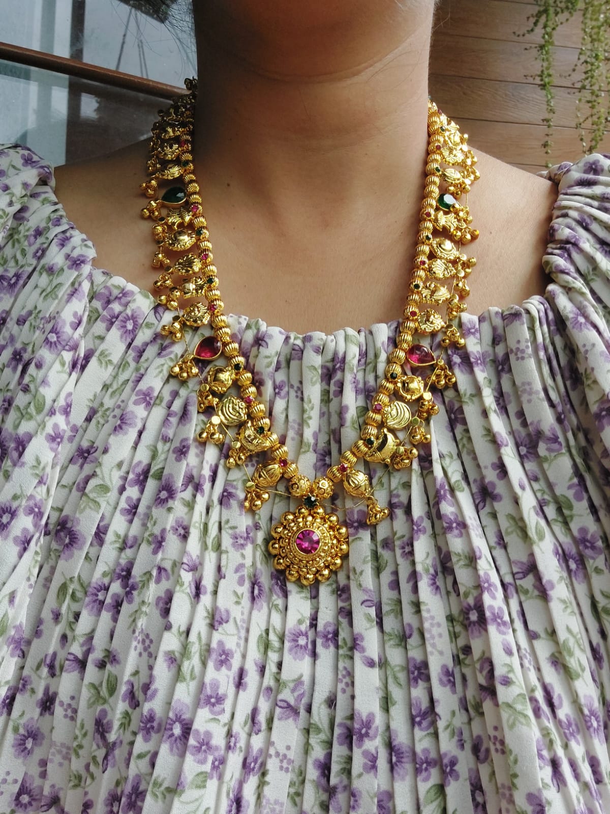 Vibrant multicolored heavy Kolhapuri saaj necklace with round beads, displayed on a floral print dress in the image.