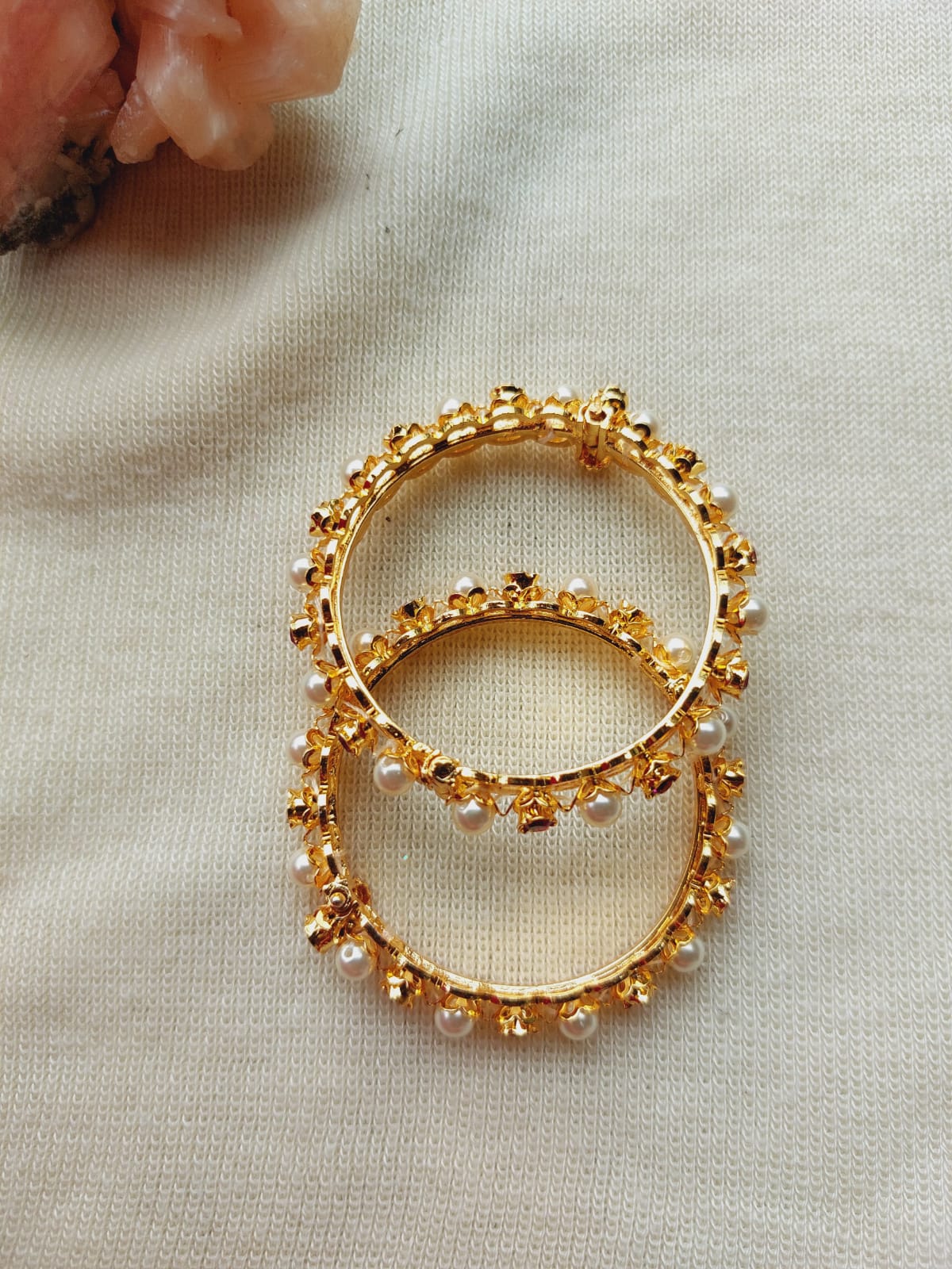 Simple gold-colored beaded rings on a light fabric background