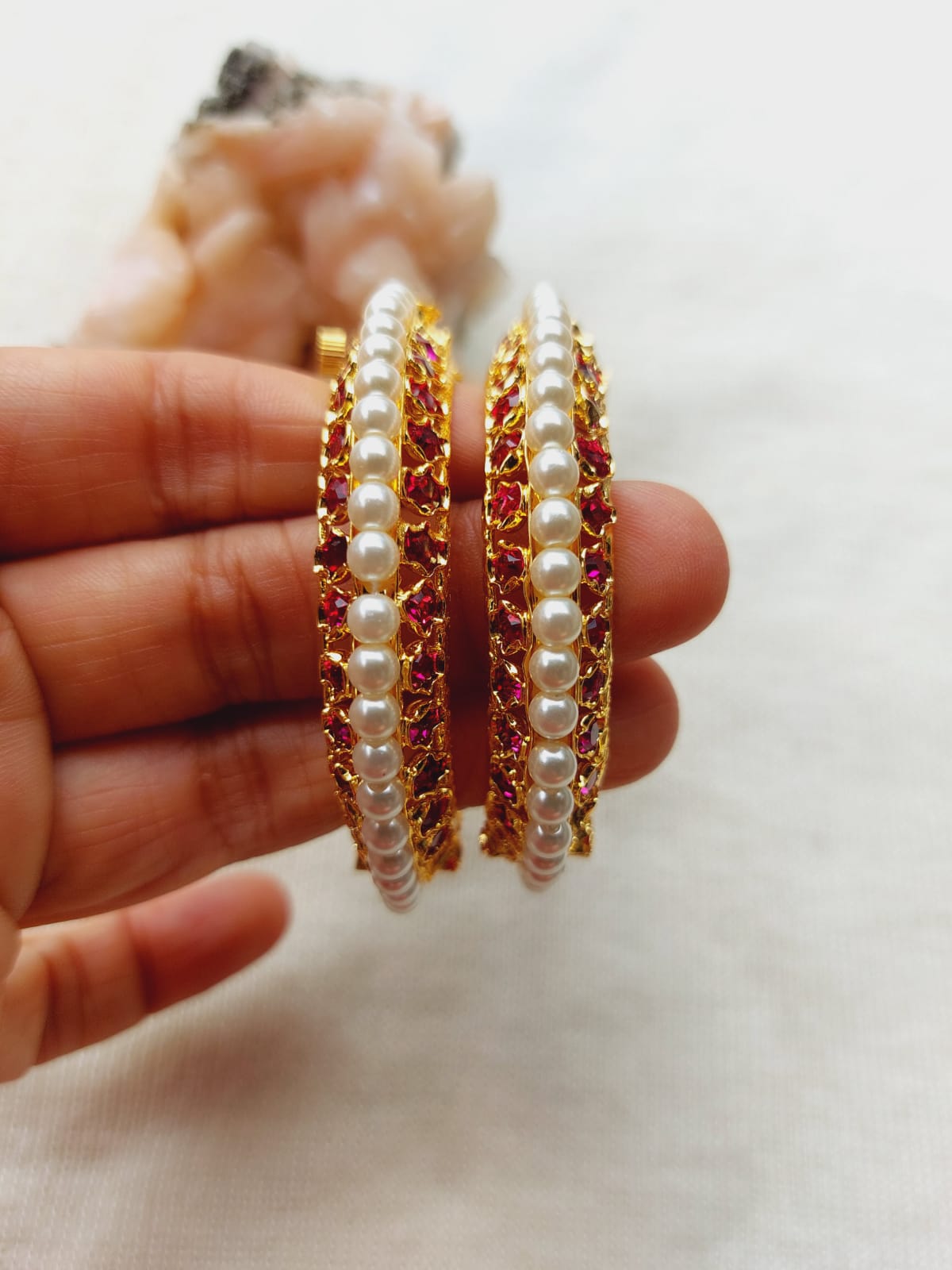 Ornate traditional Indian bangles with pearls and red gemstones, showcased against a light background in the Mugdha Jewellery Store product image.