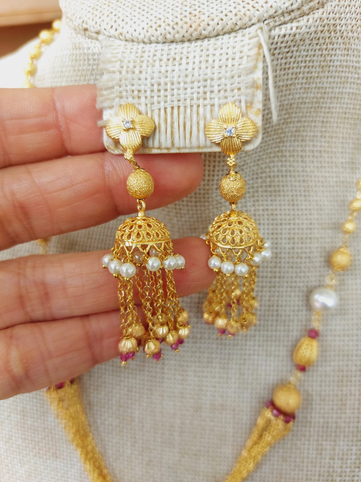 Elegant gold jhumki earrings with intricate floral patterns and dangling beads from the Mugdha Jewellery Store collection.