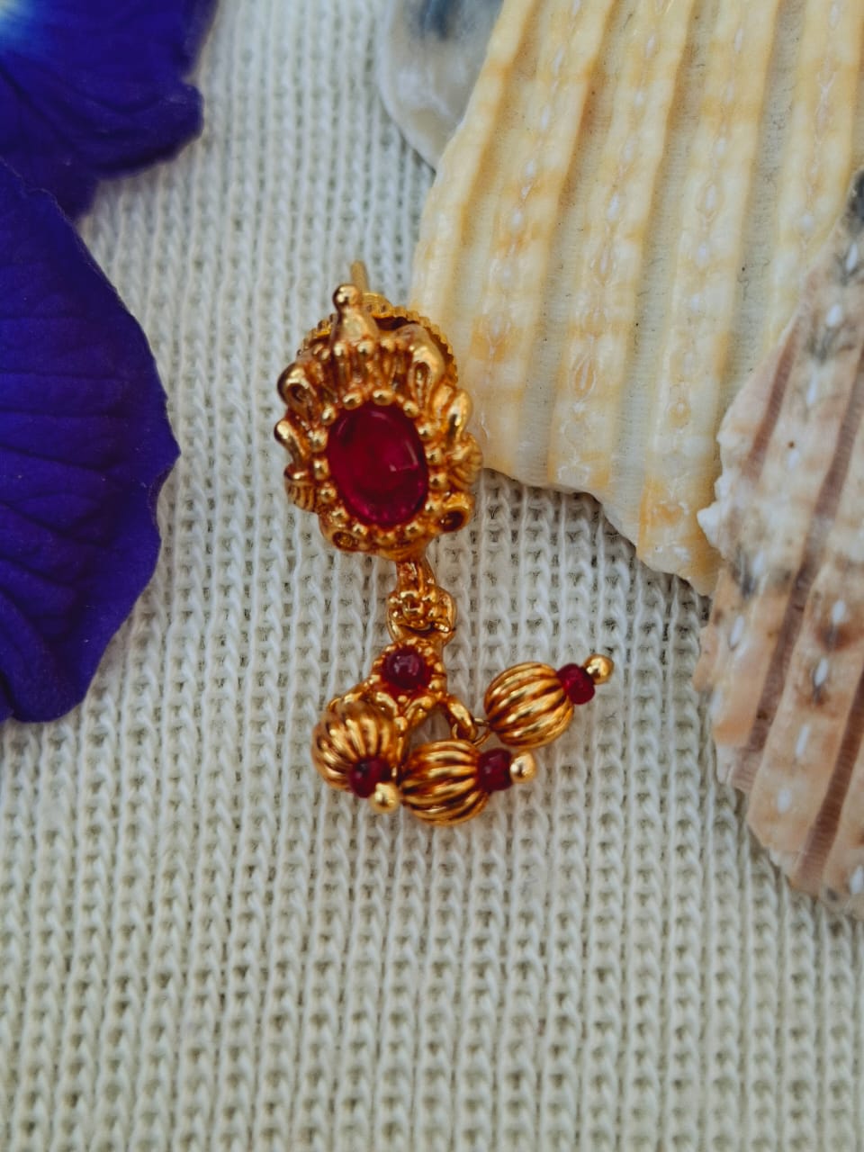 Ornate golden 9 Patti Designer Antique Chinchapeti with vibrant red gemstones on a soft textured fabric background.