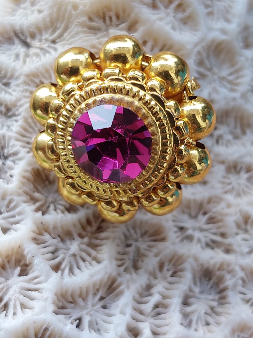 Elegant gold-tone floral earrings with a vibrant pink gemstone center, displayed on a fuzzy white background.