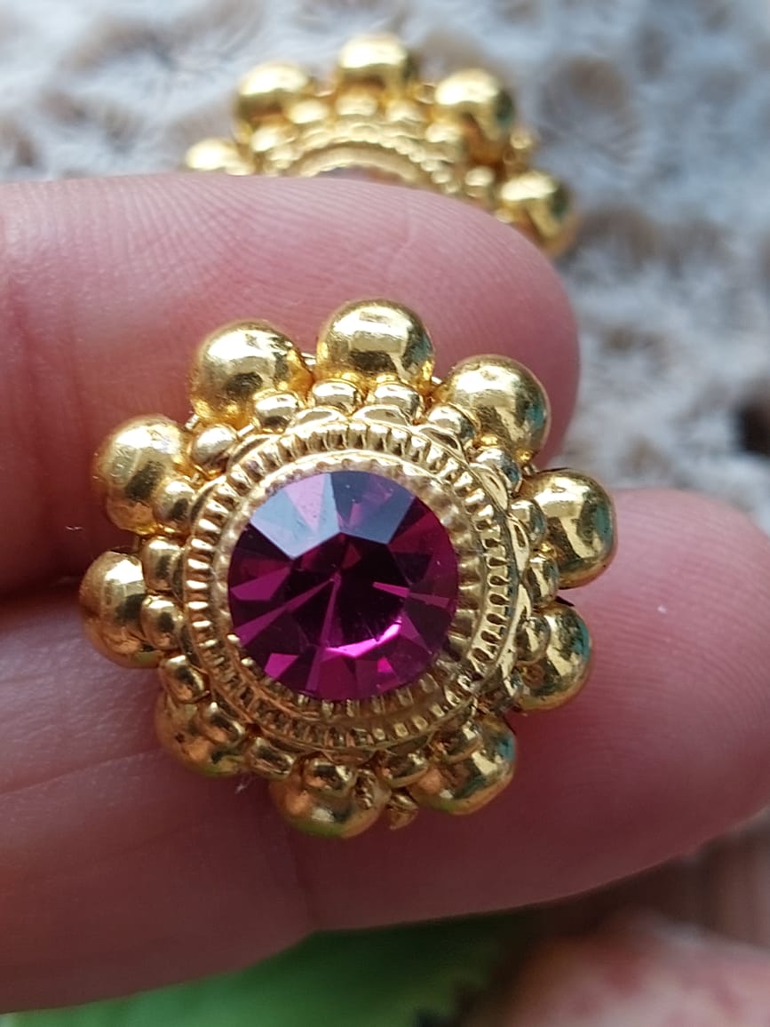 Traditional Saaj Earrings Big Size: Ornate gold-tone flower-shaped earrings with a vibrant purple gemstone centerpiece, showcased on a hand.