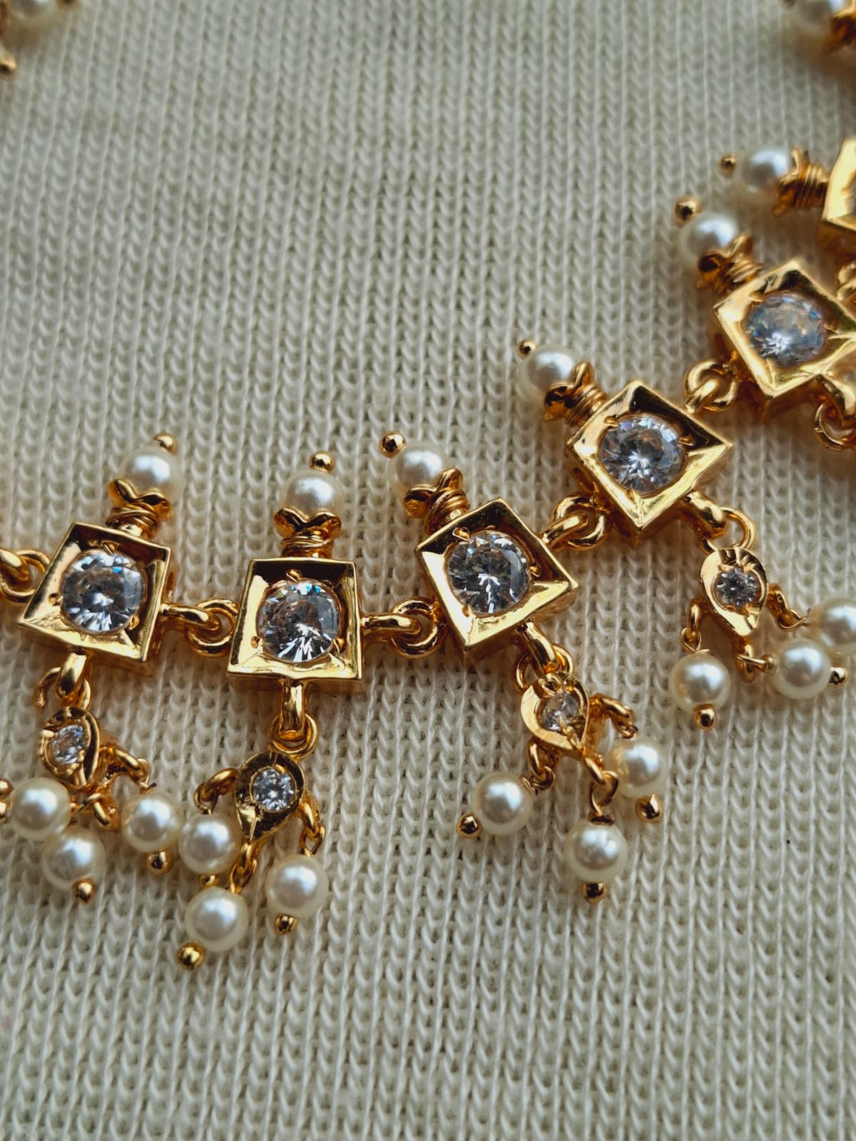 Elegant gold and pearl traditional designer jewelry set showcased on a white background.