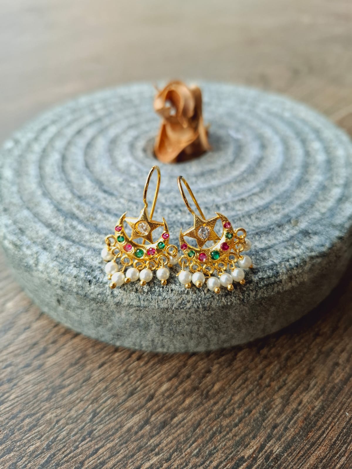 Multicoloured star-shaped chandrakor bugdi earrings on a grey stone backdrop