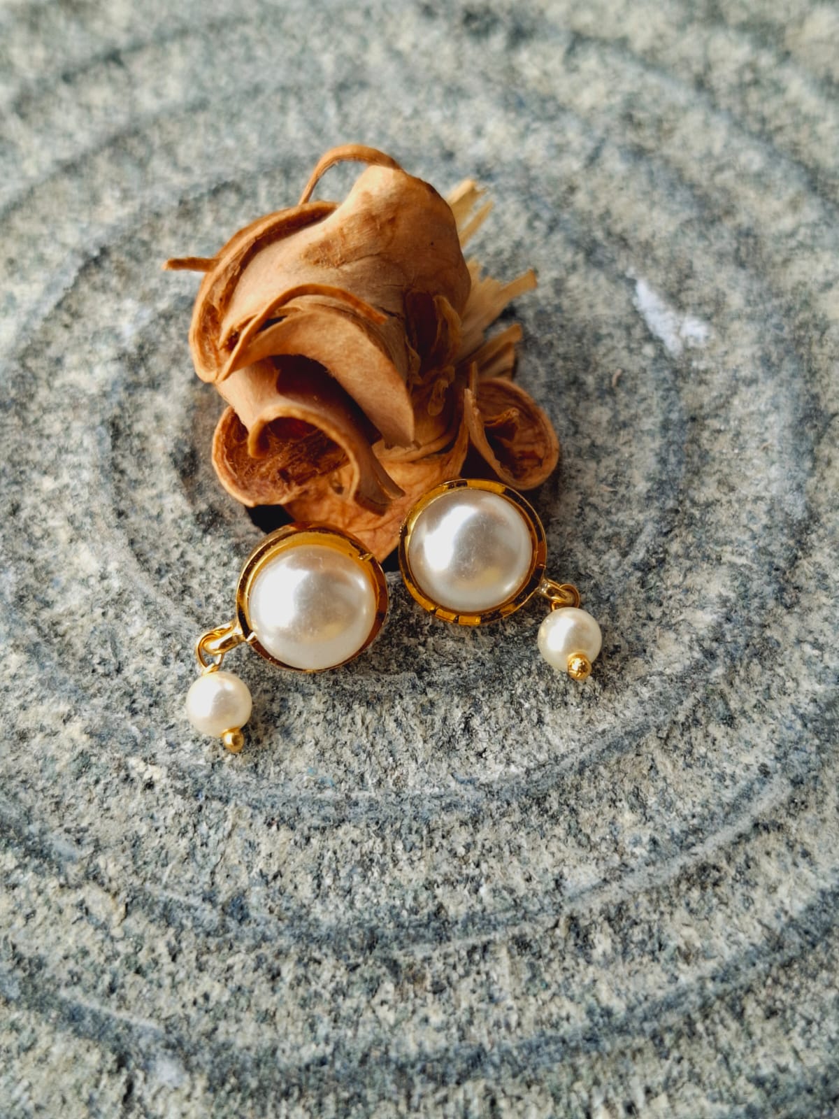 Elegant Pearl Earrings - Delicate golden rose with lustrous white pearls set on a granite background