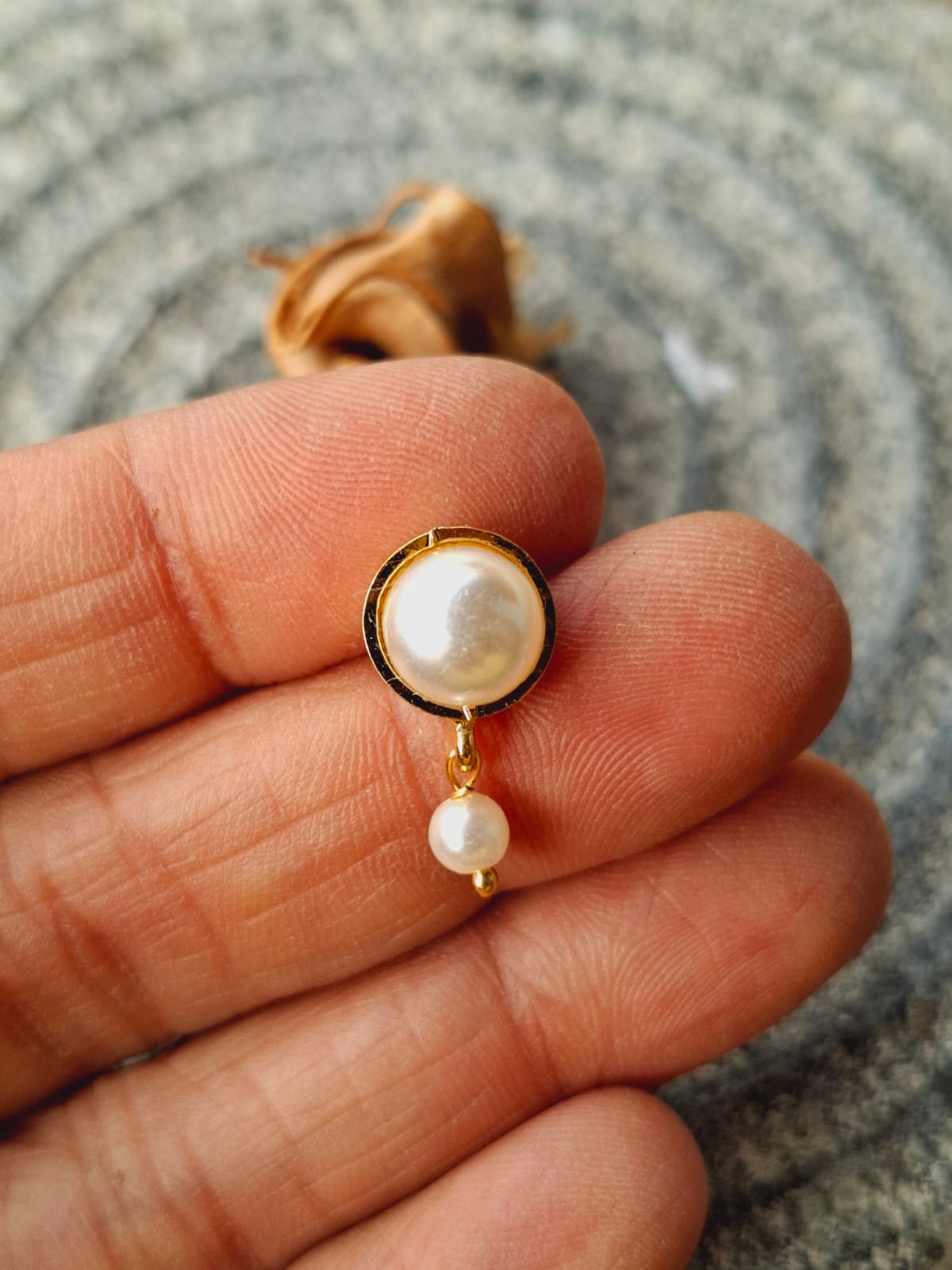 Delicate Pearl Earrings - Elegant gold-tone studs with lustrous white pearls for a timeless, sophisticated look, displayed against a soft, blurred background.