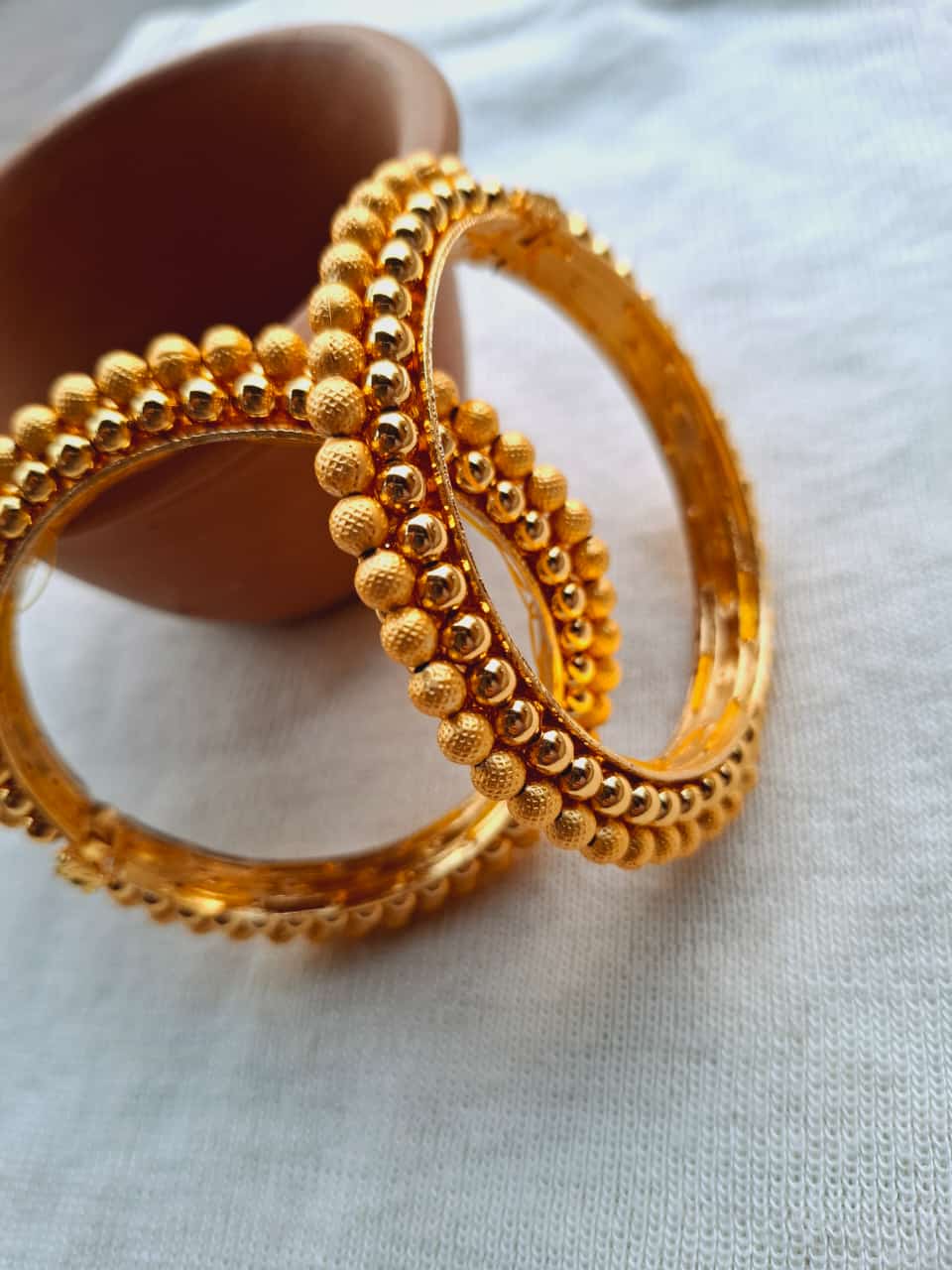 Two intricate golden bangles with detailed beaded patterns, showcasing the craftsmanship of the Royal Peshwai Tode jewelry set from the Mugdha Jewellery Store.