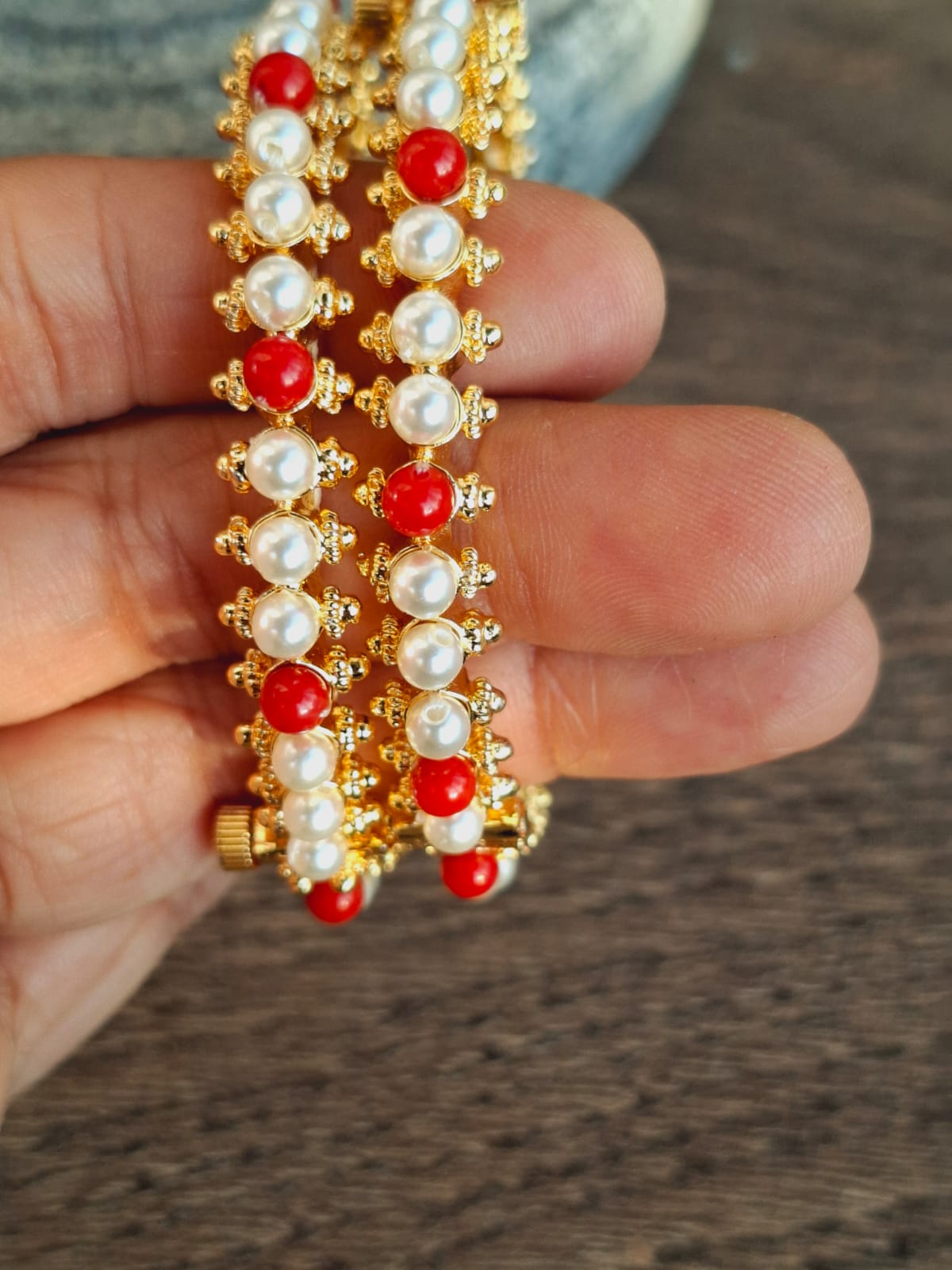 Elegant gold-toned bangles with rows of red and white gemstones, showcasing intricate craftsmanship.