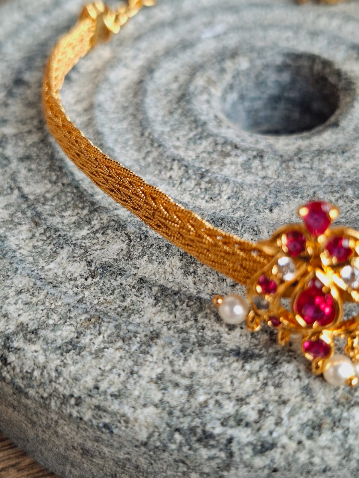 Elegant gold and ruby peacock choker necklace on grey textured surface