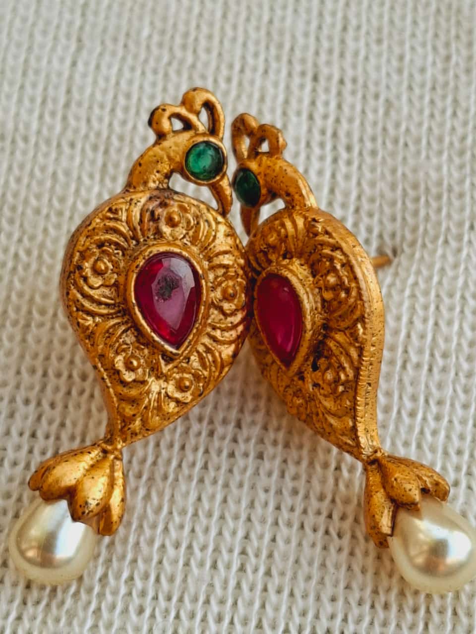 Elegant gold-toned peacock-themed mangalsutra pendant with vibrant ruby and emerald accents, adorned with lustrous pearl drops.