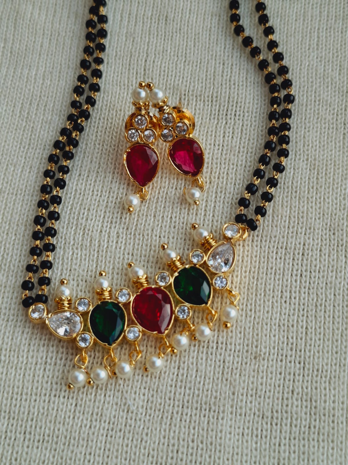 Multicolored gemstone mangalsutra with golden beads, red and green accents, and pearl detailing on a 24-inch chain.