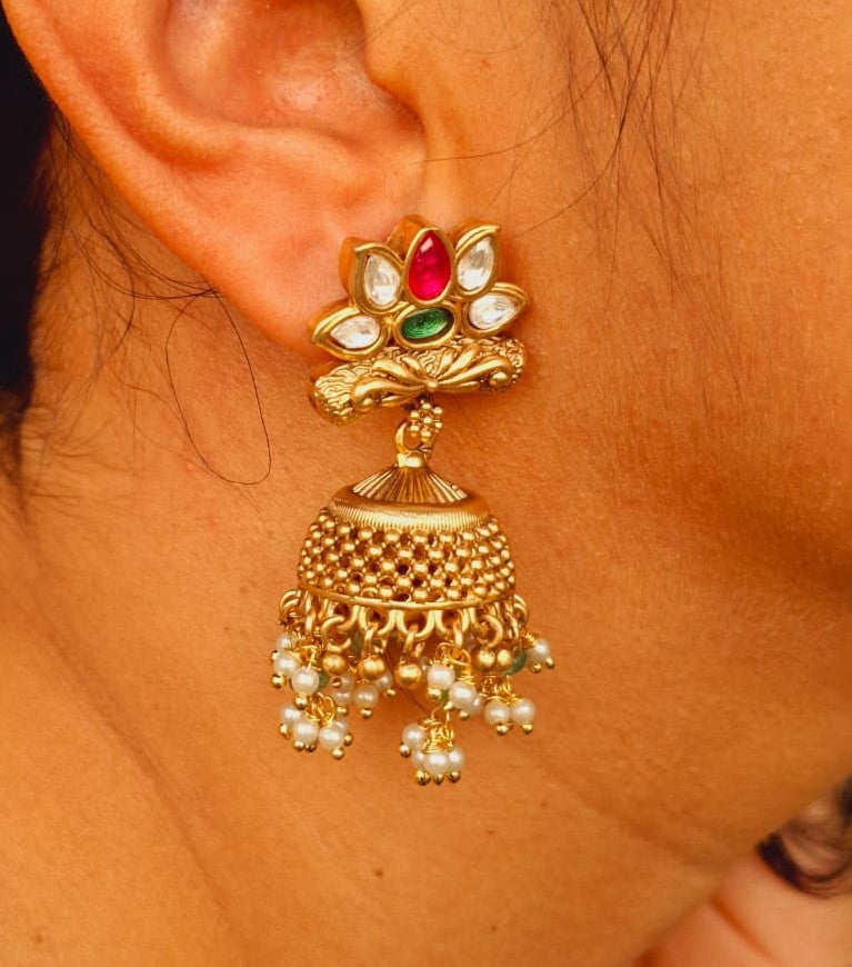 Stunning jeweled gold jhumka earrings with colorful gemstones, cascading pearls, and intricate filigree design from the Mugdha Jewellery Store.