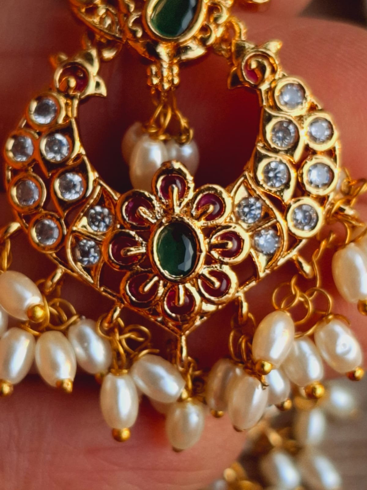 Ornate gold-toned earrings with intricate floral motifs, sparkling gemstones, and lustrous pearls