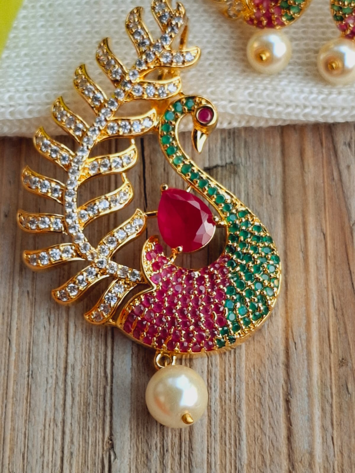 Elegant peacock pendant set with sparkling crystals and pearls on wooden surface