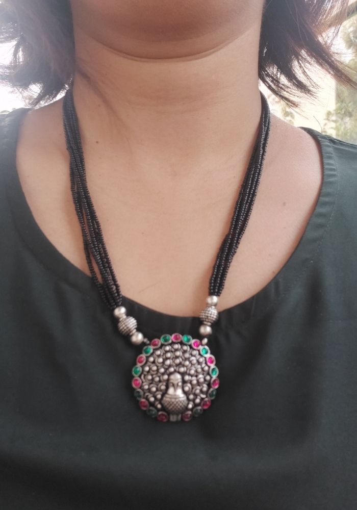 Elegant oxidized short mangalsutra with colorful beads and intricate pendant design, showcased on a model's neck.