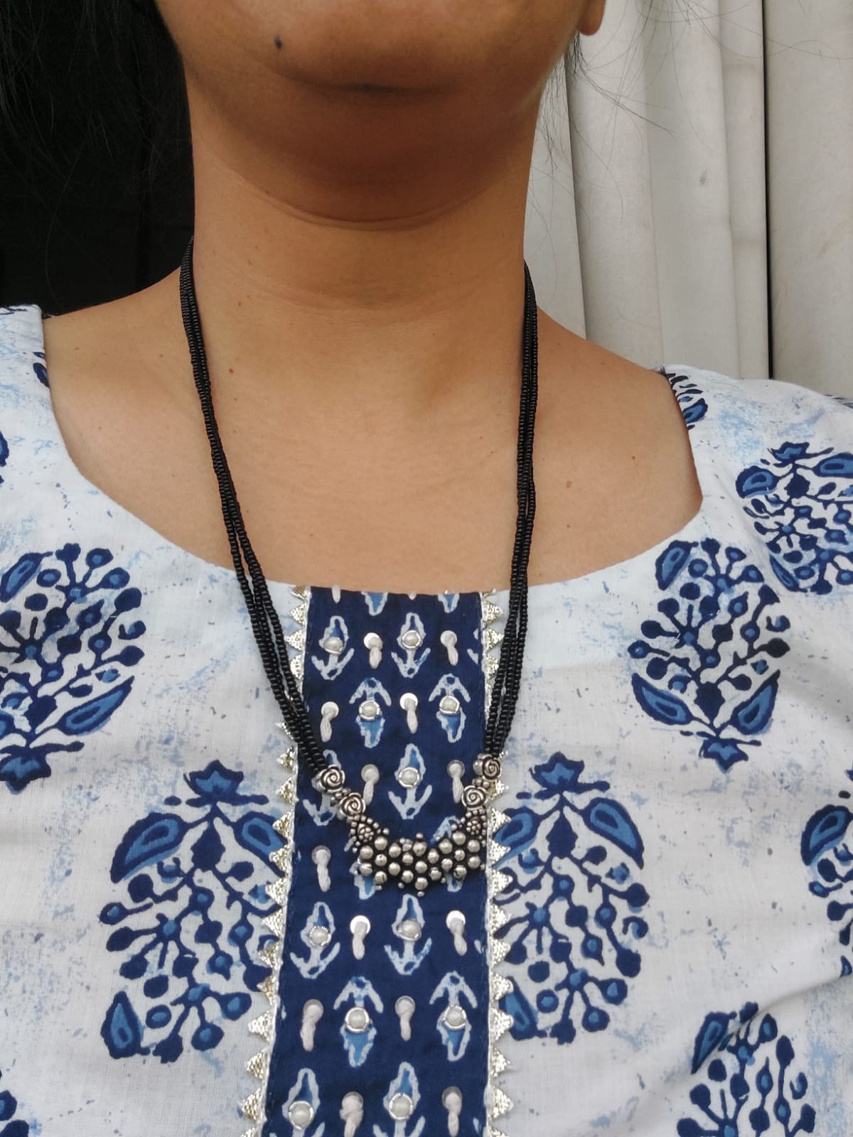 Oxidised short mangalsutra necklace with intricate blue and white patterned textile in the image