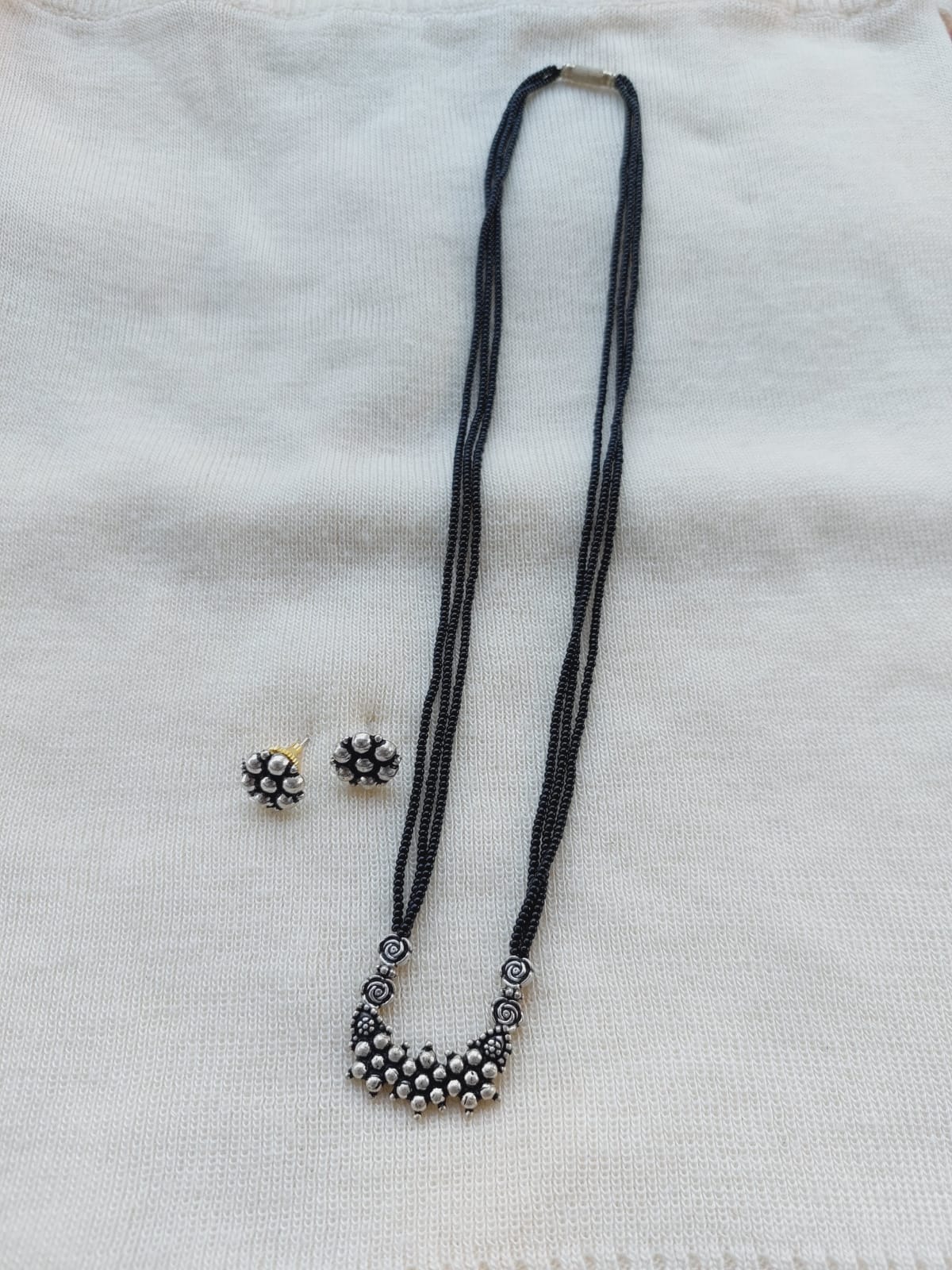 Oxidised short mangalsutra with intricate floral design and matching earrings on white background
