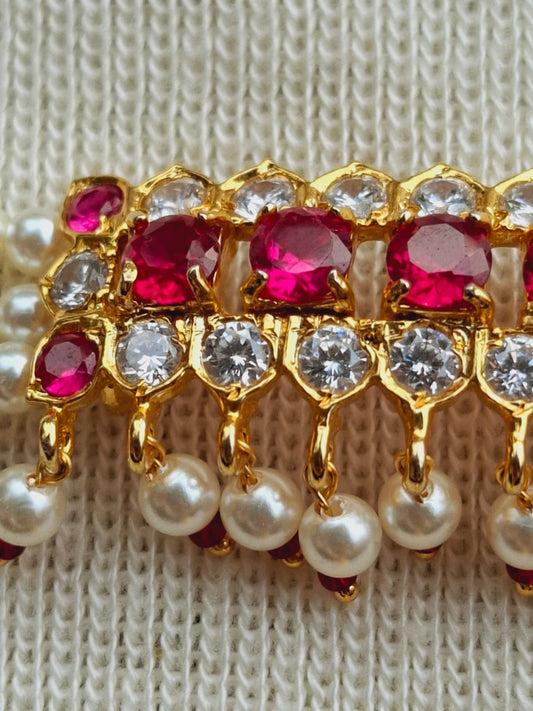 Elegant ruby and diamond choker necklace with pearls, displayed on a knitted fabric background.